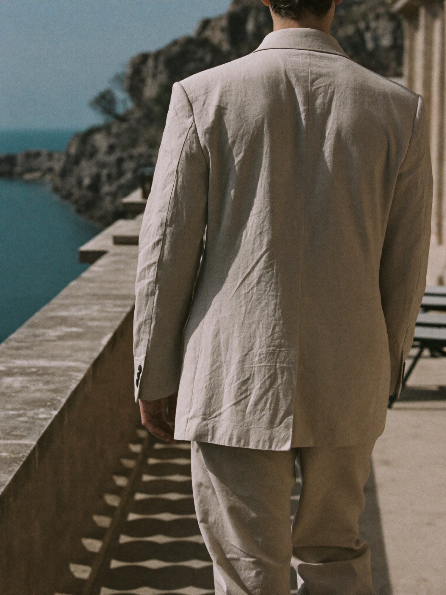 Man walking on a stone terrace in a soft linen jacket